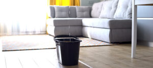 Water droplets leaking in bucket from ceiling, damaged roof, house renovation